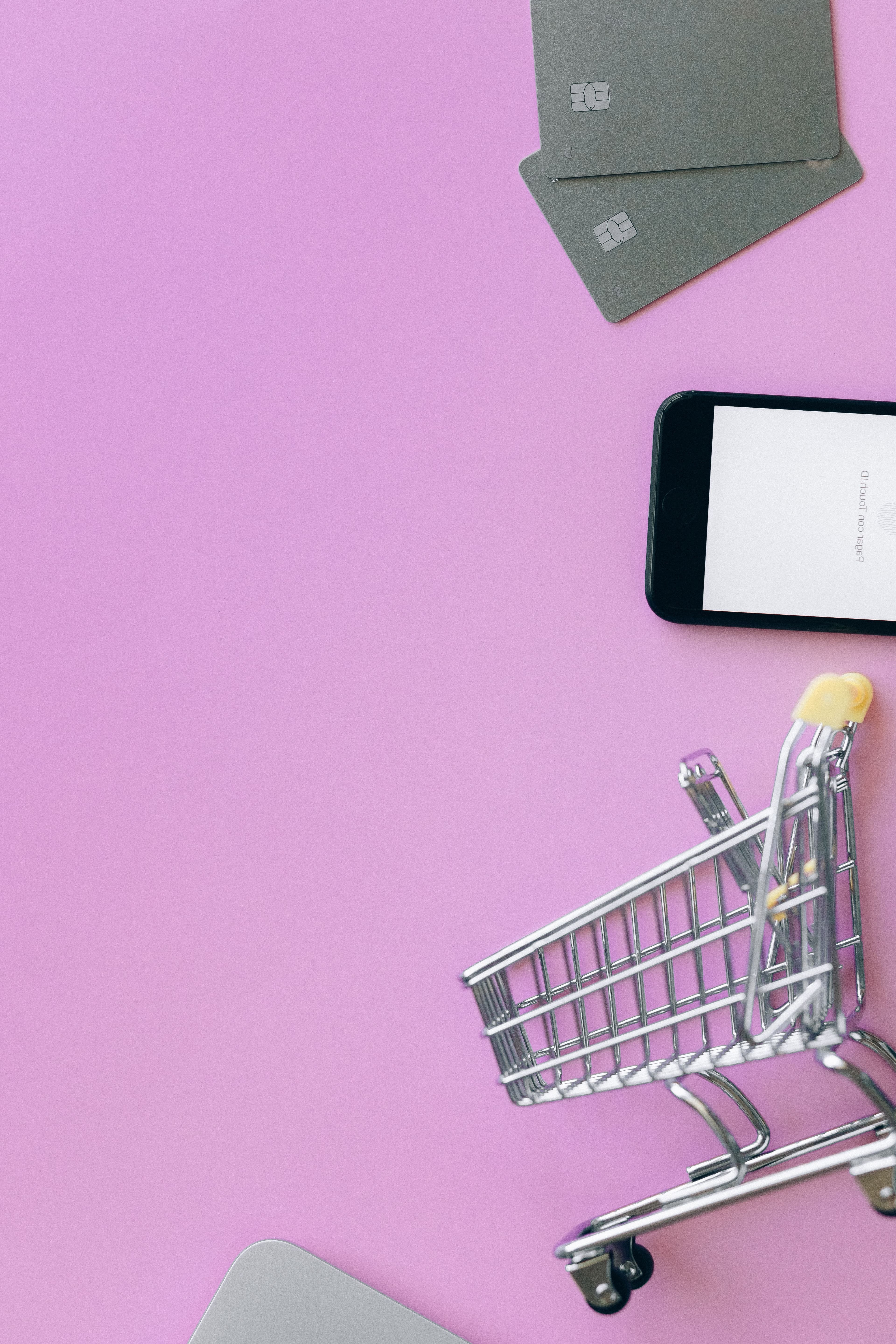 Credit cards, smartphone, and shopping cart on a purple background